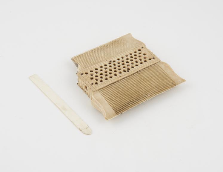 Double-sided ivory comb with toilet implement slotting through