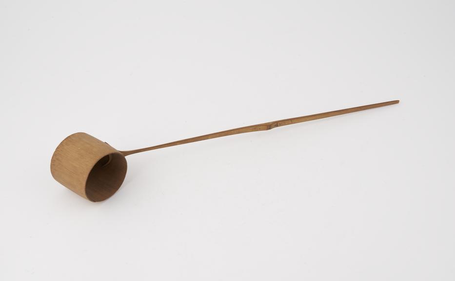 Wooden cylindrical ladle with long wooden handle used in tea