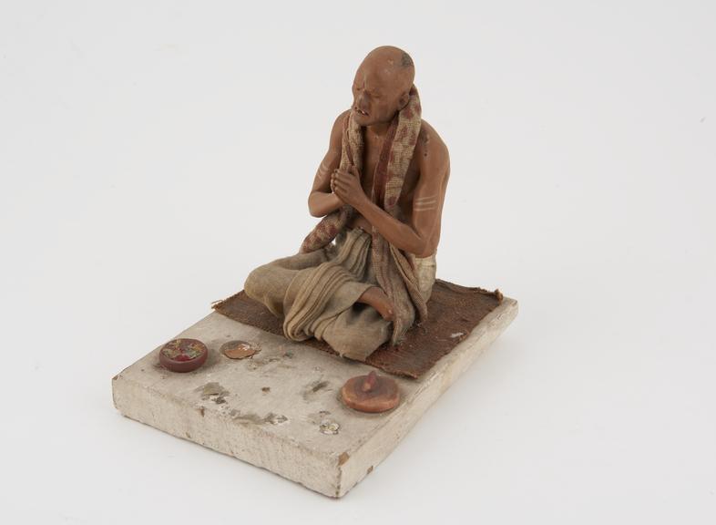 Painted wooden figure of seated man in half-lotus position