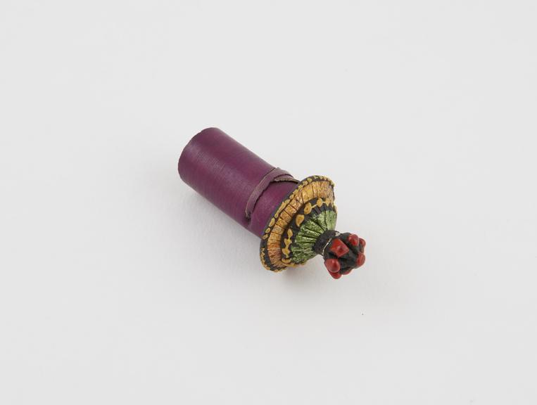 Earplug of rolled purple palm-leaf with polychrome two-tiered