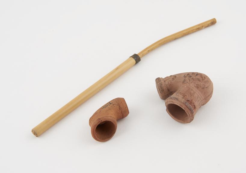 Two red clay tobacco pipes, one bowl in elbow form