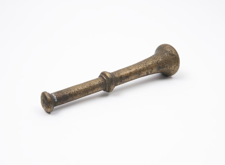 Brass pestle with central flange and button-shaped finial