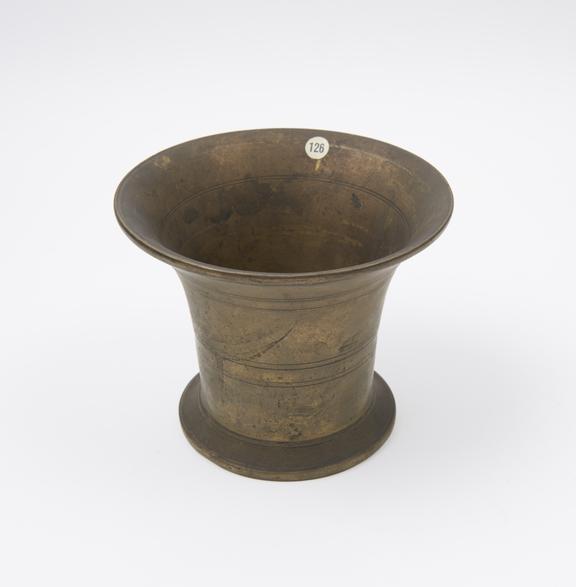 Brass bell shaped mortar with flat protruding base, flaring rim