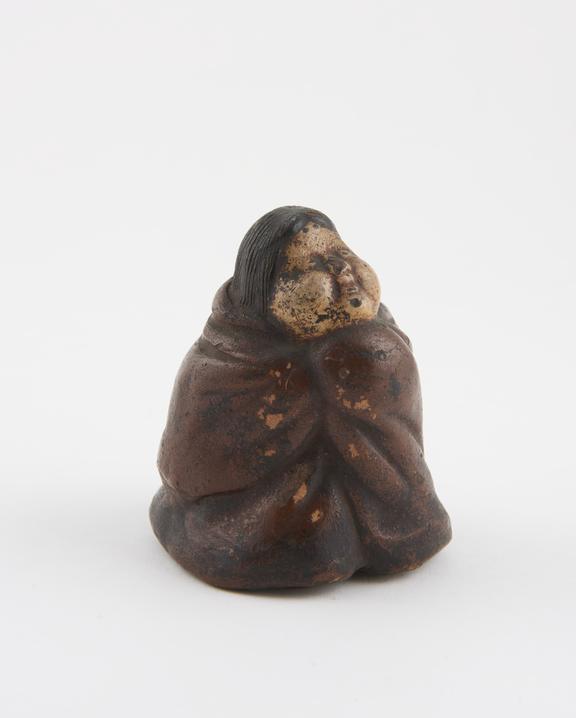 Pottery statue of a crouching woman, wrapped in a cloak