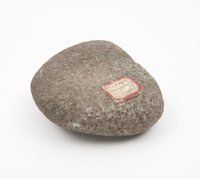 Semicircular grey stone pounder with depression on either side