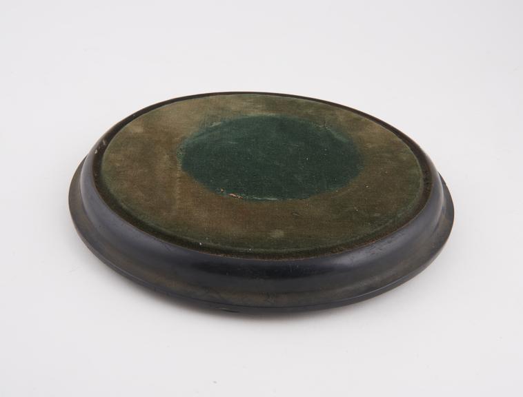 Circular wooden stand, painted black with green velvet top