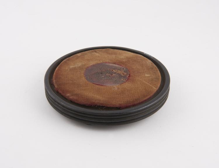 Circular wooden stand, painted balck with faded red velvet top