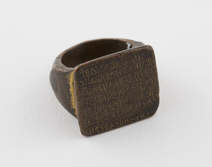 Bronze finger ring with square bezel bearing 7 lines of script