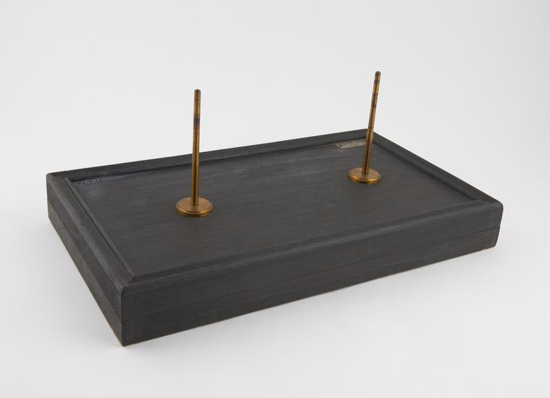 Rectangular wooden stand with 2 brass pins for holding a