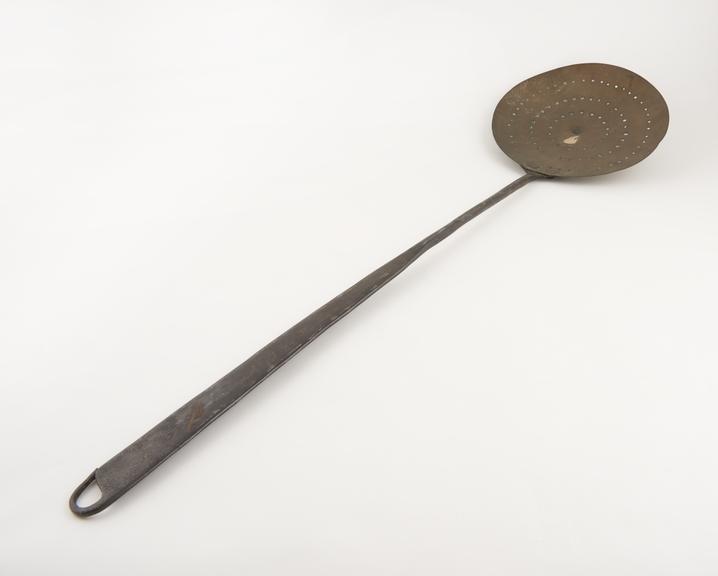 Circular brass strainer attached to long steel handle, European