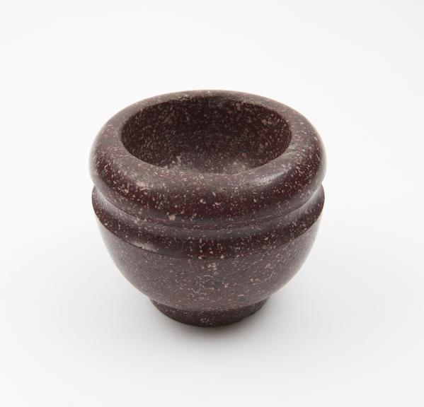 Small maroon porphyry (?) mortar with foot ring and groove