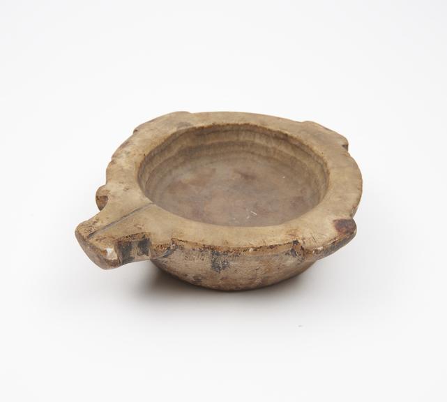 Shallow bowl-like mortar in cream stone, flat base