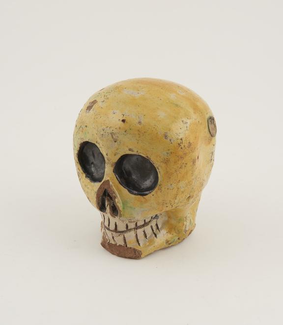 Crude deathshead skull of yellow glazed earthenware