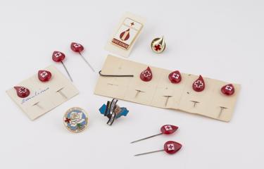 14 blood donor badges; 10 red blood drop pins with white crosses