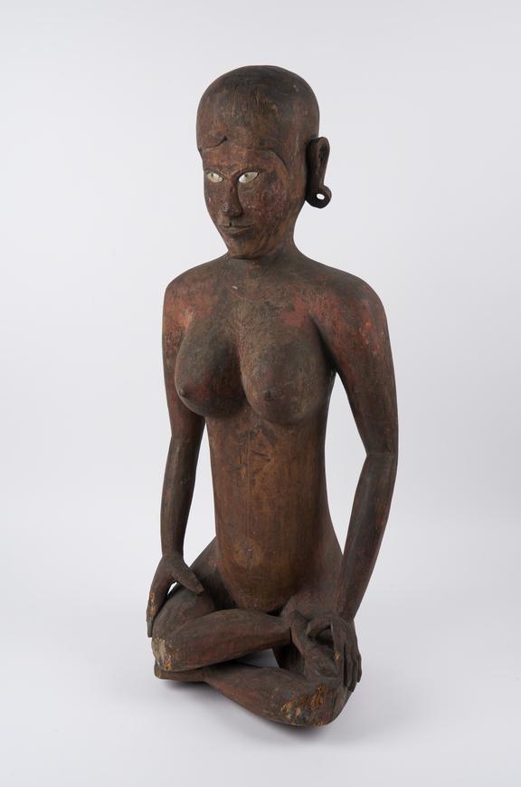 Painted and carved wooden figure of seated female, legs crossed