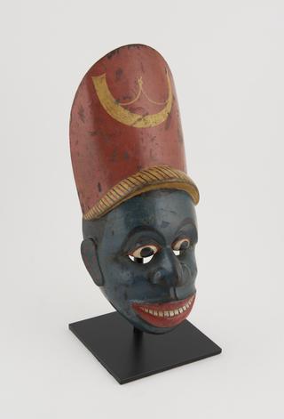 Painted face mask representing black character in Kolam play