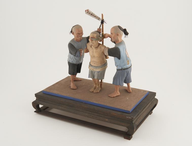 3 painted wooden figures depicting the execution of a prisoner