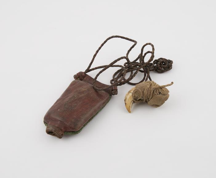 Red leather amulet case with small cloth wrapped tusk attached