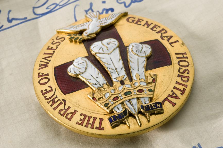 Round brass badge decorated with red enamel cross and white