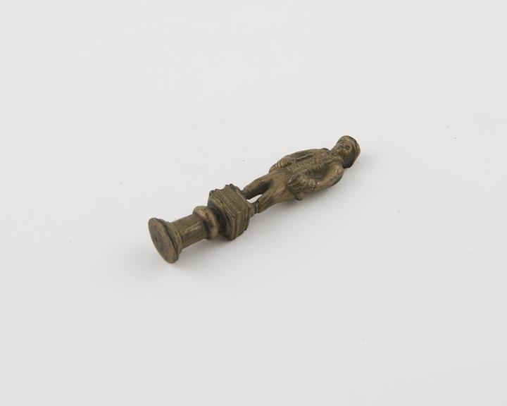 Pipe tamper, in form of figure of farmer on stand, brass