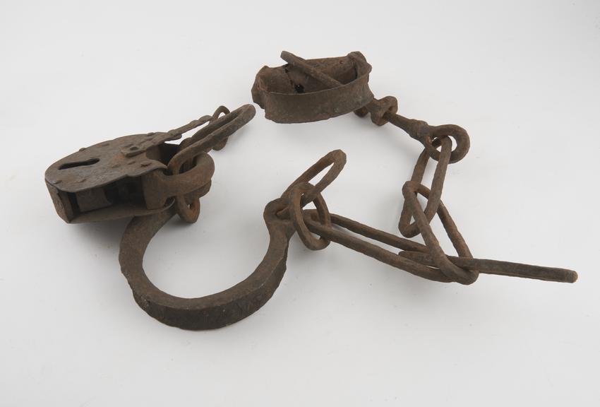 Pair of leg irons linked by iron chain and secured by padlock