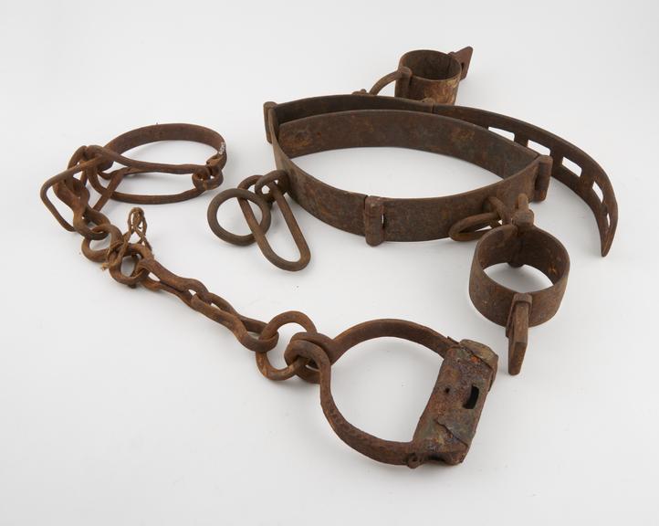 Wrist iron with attached manacles and associated leg irons