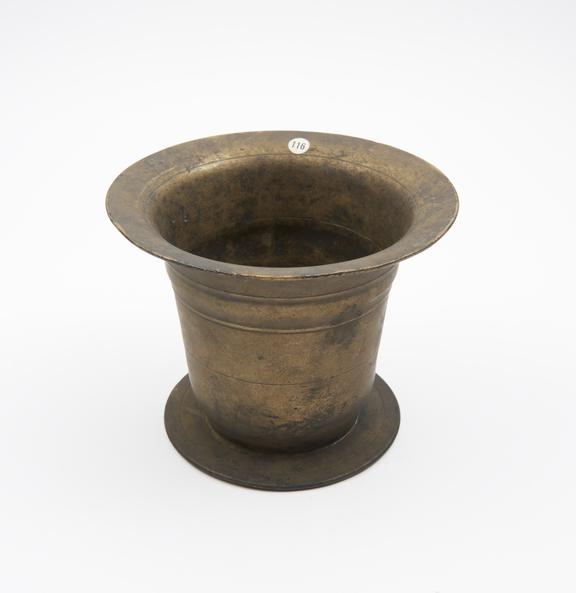 Brass bell-shaped mortar with flat base which protrudes to form