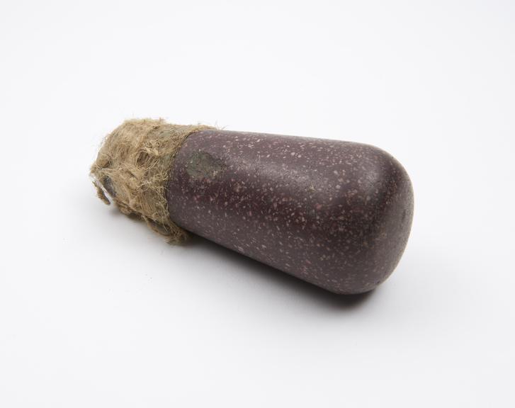 Red stone pestle with fibrous binding round butt, no provenance