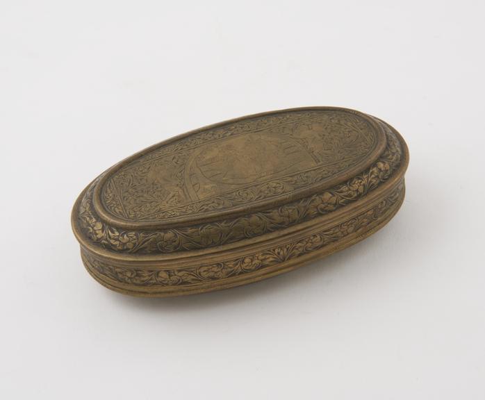 Oval brass tobacco box, hinged lid, engraved panels on lid