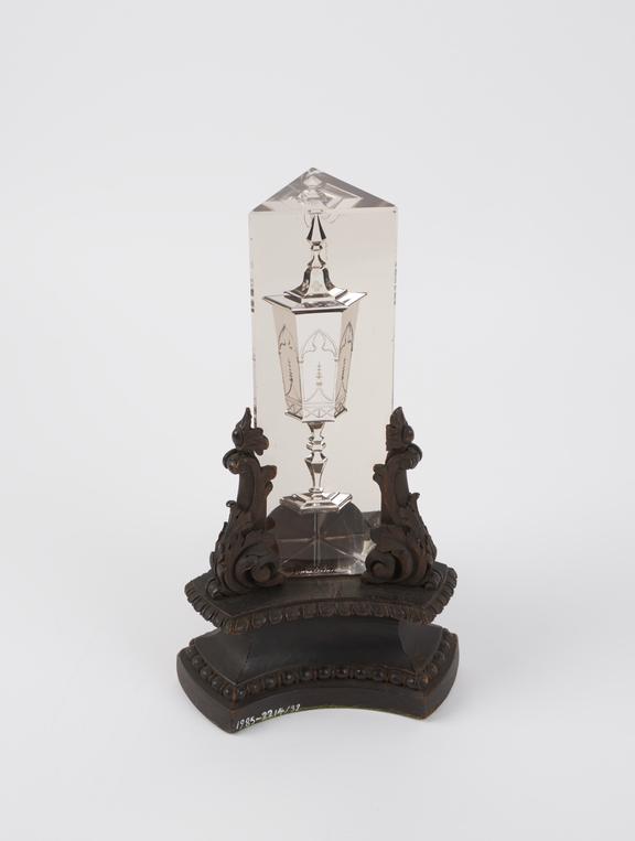 Glass prism showing the illusion of a goblet on ornate, carved