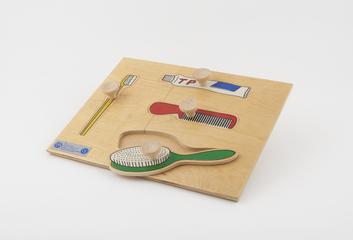 Wooden puzzle board showing toothbrush, toothpaste, comb and hairbrush