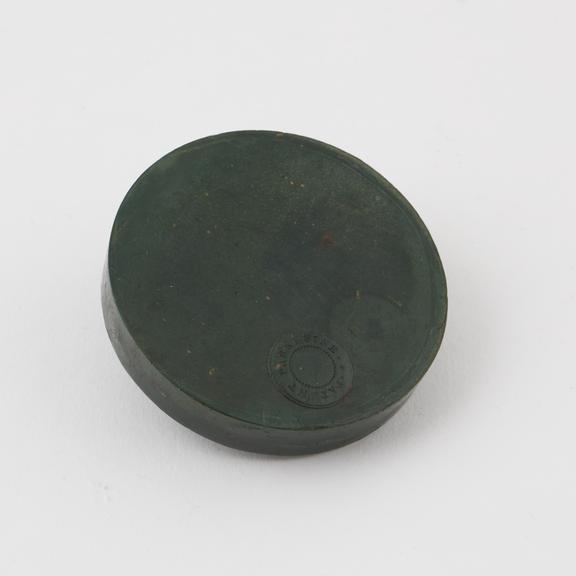 Flat disc of bottle green Parkesine, sample