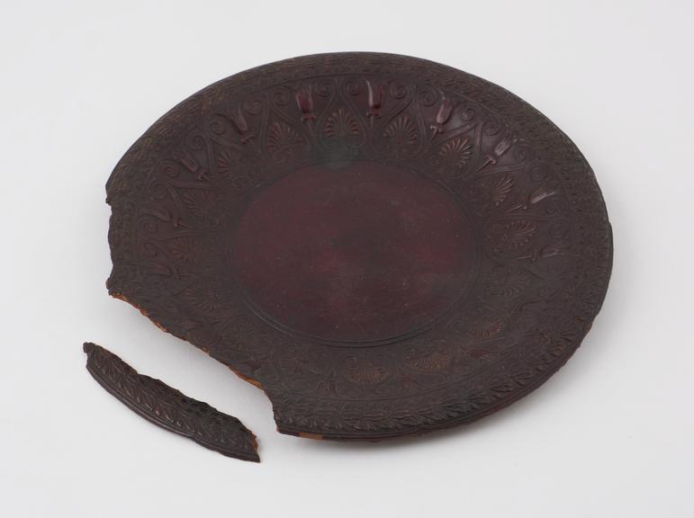 Circular moulded dish of maroon Parkesine, with ornate border