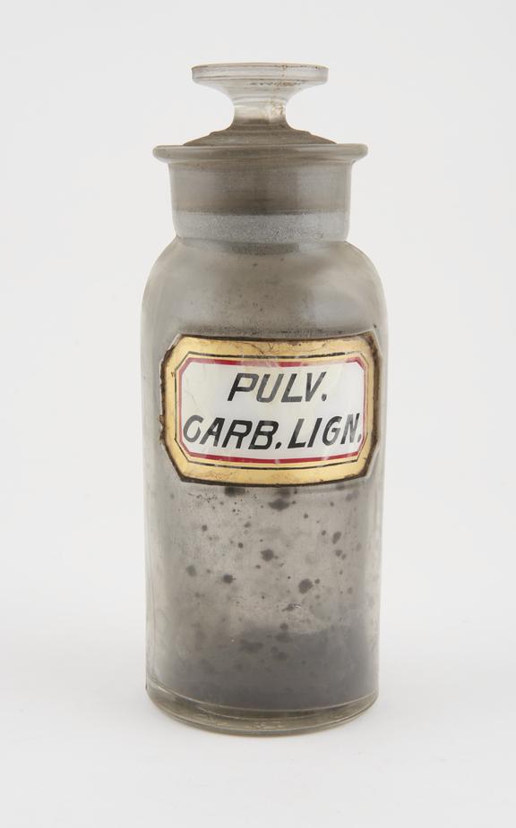 Bottle, clear glass, with contents, for powdered charcoal, USA