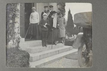 Untitled black and white photograph showing a group of people standing on steps outside a house
