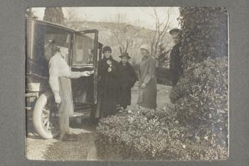 Untitled black and white photograph showing a group of people about to get into a motor car