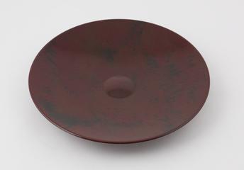 Shallow circular dish moulded in mottled ochre and black phenolic