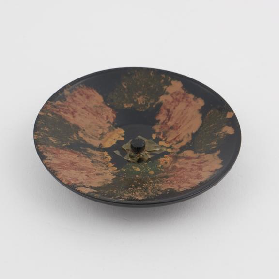 Circular ashtray of black and multi coloured phenolic