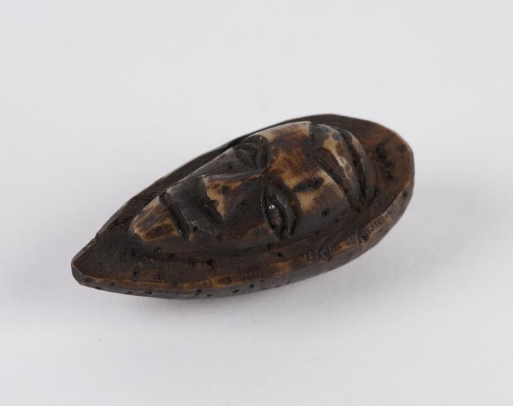 Amulet in the form of a face, carved from a fruit stone