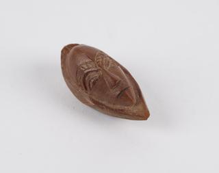 Amulet in the form of a face carved from the fruit of a stone