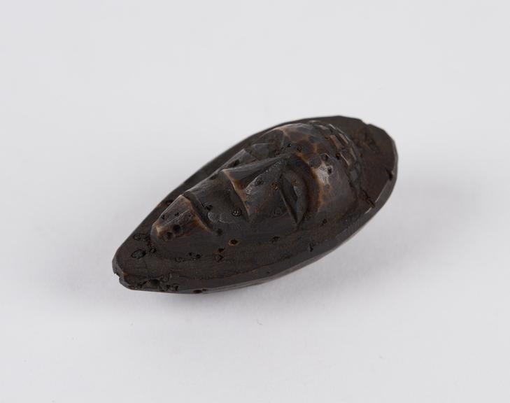 Amulet, in the form of a face carved out of a fruit stone