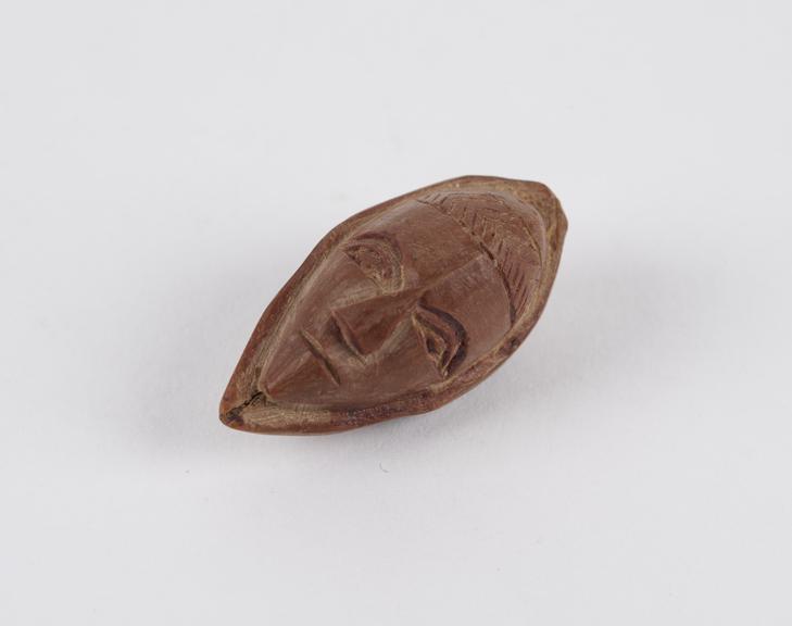 Amulet, in the form of a face, carved out of a fruit stone