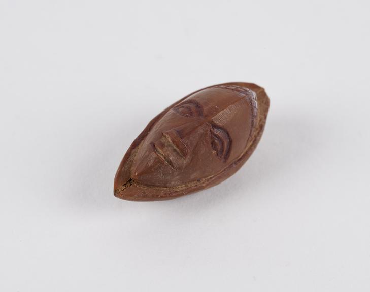 Amulet, in the form of a face, carved out of a fruit stone