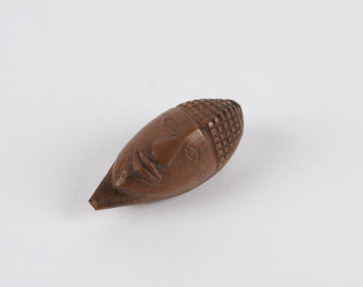 Amulet, in the form of a face, carved from a fruit stone