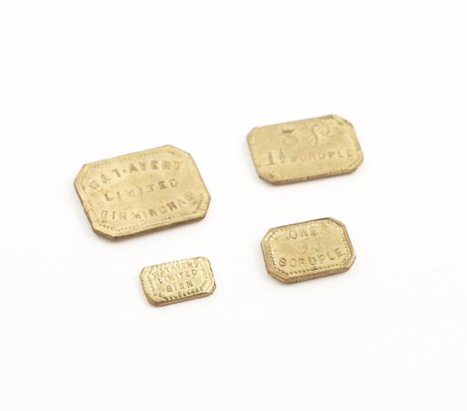 Set of 4 rectangular brass scruple weights, in paper wrapping