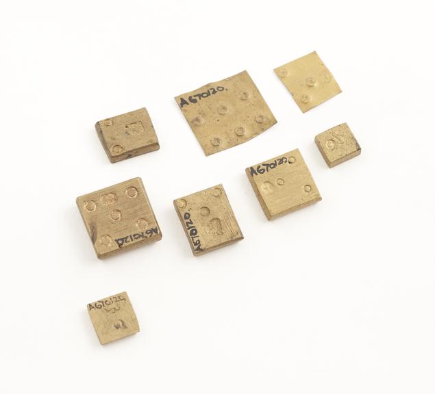 Set of 8 roughly square brass weights, of varying value