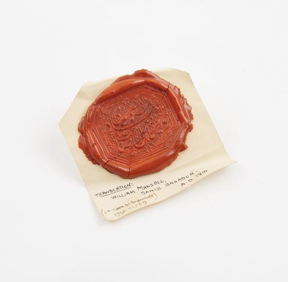 Seal in orange sealing wax, on slip of white paper