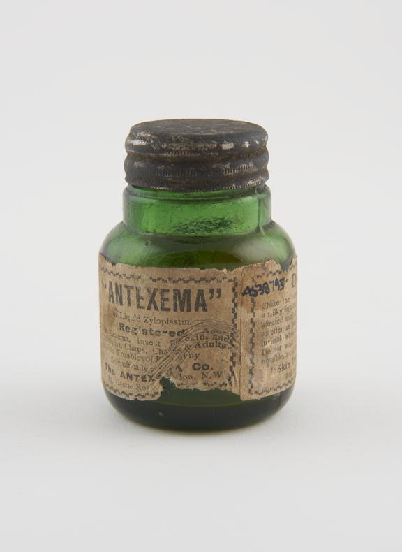 Empty, cylindrical, green glass bottle with metal screw cap