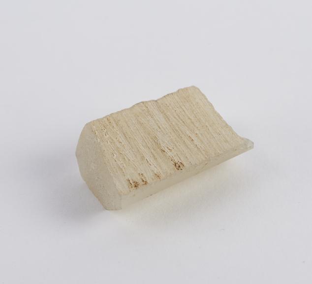 Small piece of polished rock, rectangular with berelled side