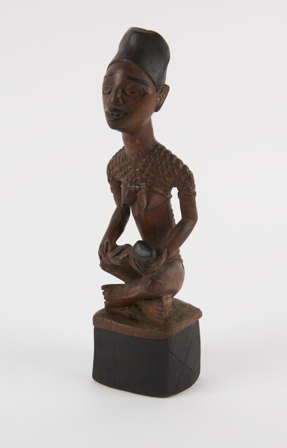 Carved wood figure of woman seated cross-legged with child on